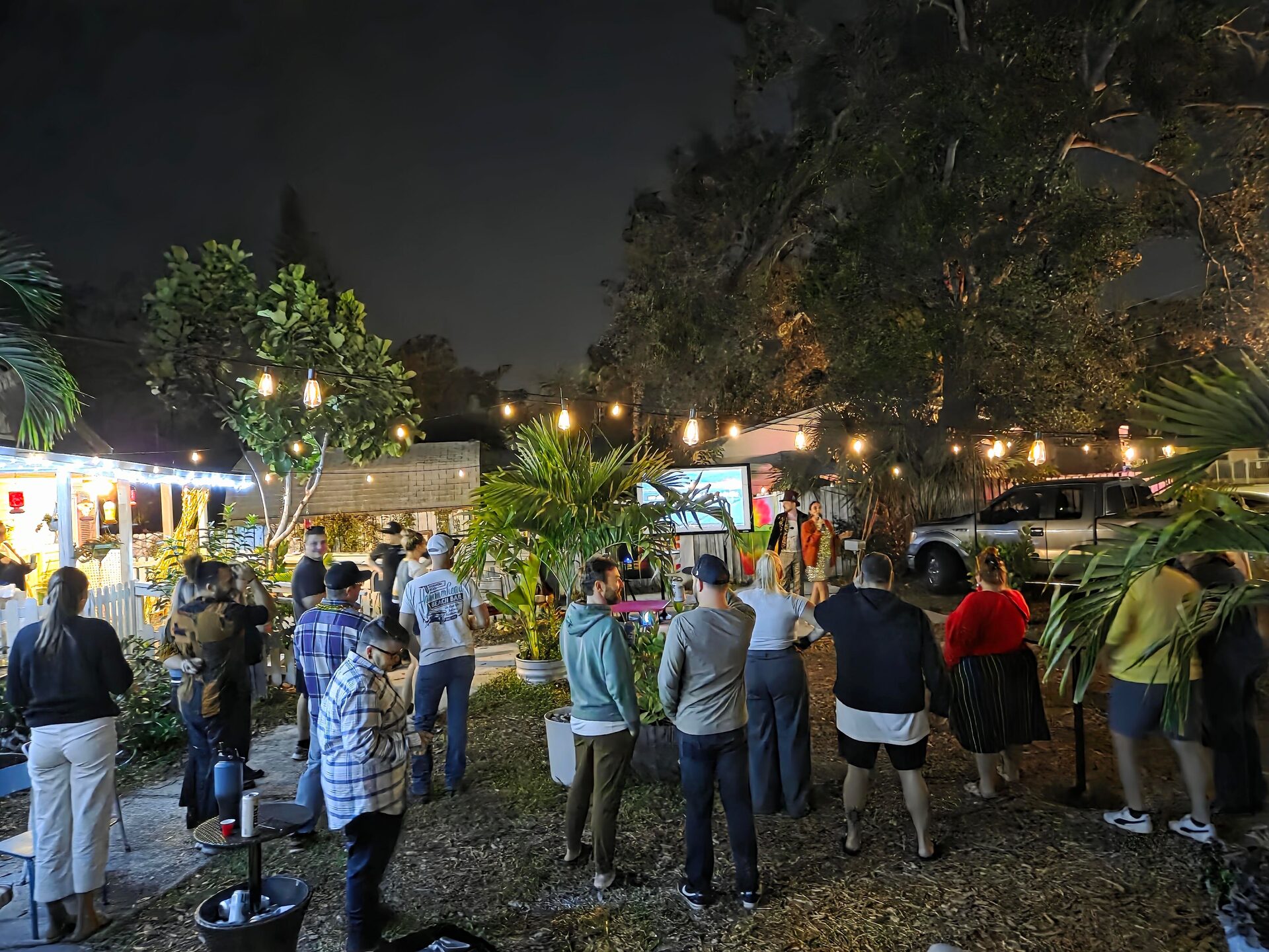 Guests gathered outdoors under string lights for an evening birthday celebration