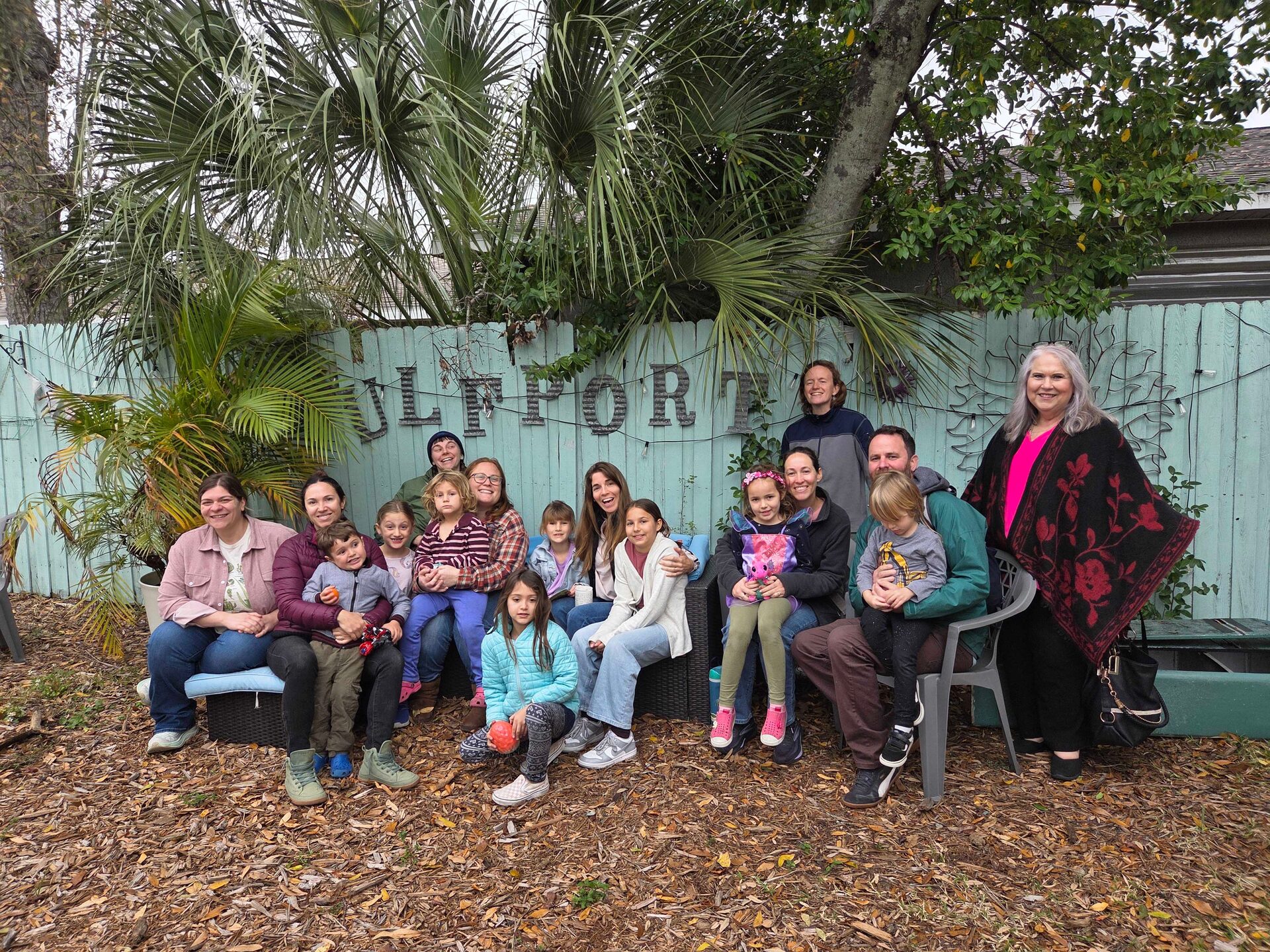 A large group of families with children gathered together for a community photo in the garden