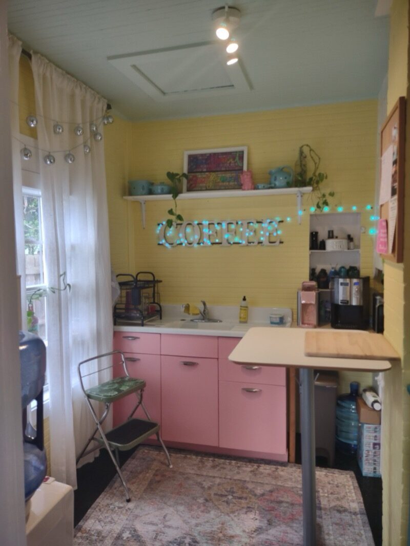 Bright coffee nook with pink cabinets and a lit-up COFFEE sign